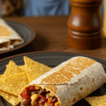 A finished, homemade Bean & Bacon Burrito on a plate being enjoyed at a fun and casual family dinner.