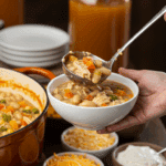 A large pot of homemade Creamy White Chicken Chili being served at a fun fall party with a toppings bar.