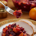 A beautiful plate of a homemade, elegant, and vibrant Beet and Blood Orange Salad, being served with a thick slice of a roasted turkey at a Thanksgiving dinner.