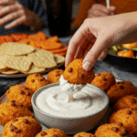 A large platter of homemade, spooky, and adorable "Chicken Pumpkins" being served as the centerpiece appetizer at a fun and casual Halloween party.