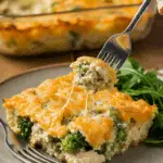 A beautiful, cheesy slice of homemade Chicken and Broccoli Pasta Casserole being served with a side of a simple green salad for a family dinner.