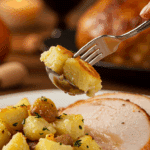 A beautiful plate of a homemade, elegant, and crispy Smashed Potatoes, being served with a thick slice of a roasted turkey at a Thanksgiving dinner.