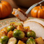 A beautiful plate of a homemade, elegant, and colorful Glazed Brussels Sprouts and Potatoes, being served with a thick slice of a roasted turkey at a Thanksgiving dinner.