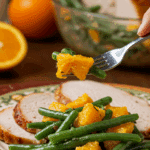 A beautiful plate of a homemade, elegant, and vibrant Green Bean and Orange Salad, being served with a thick slice of a roasted turkey at a Thanksgiving dinner.