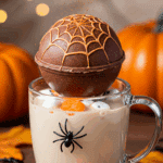 A magical action shot of a homemade, spooky Halloween Hot Cocoa Bomb "exploding" and releasing cocoa and marshmallows into a large glass mug of hot milk.