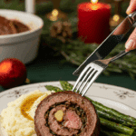 A beautiful plate of a homemade, thick, and juicy, spiral-stuffed slice of a Steak Roulade, being served with mashed potatoes and roasted asparagus at a Christmas dinner.