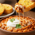 A beautiful, cheesy serving of homemade Pizza Beans being enjoyed with a piece of crusty garlic bread for a family dinner.