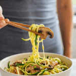 A cozy bowl of homemade, healthy Keto Ramen with Zucchini Noodles being enjoyed with chopsticks for a casual, healthy lunch.