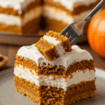 A beautiful, tall, and layered slice of homemade, creamy Pumpkin Delight being served on a dessert plate at a Thanksgiving dinner.