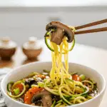 A cozy bowl of homemade, healthy Vegan Ramen with Zucchini Noodles being enjoyed with chopsticks for a casual, healthy lunch.
