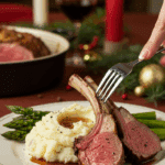 A beautiful plate of a homemade, thick, and juicy Roasted Rack of Lamb, being served with creamy mashed potatoes and roasted asparagus at a Christmas dinner.